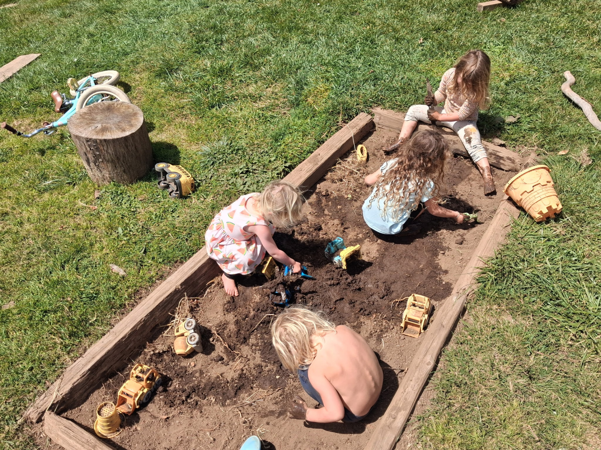 Four children digging together in a mud and sand pit at our McKinleyville outdoor school
